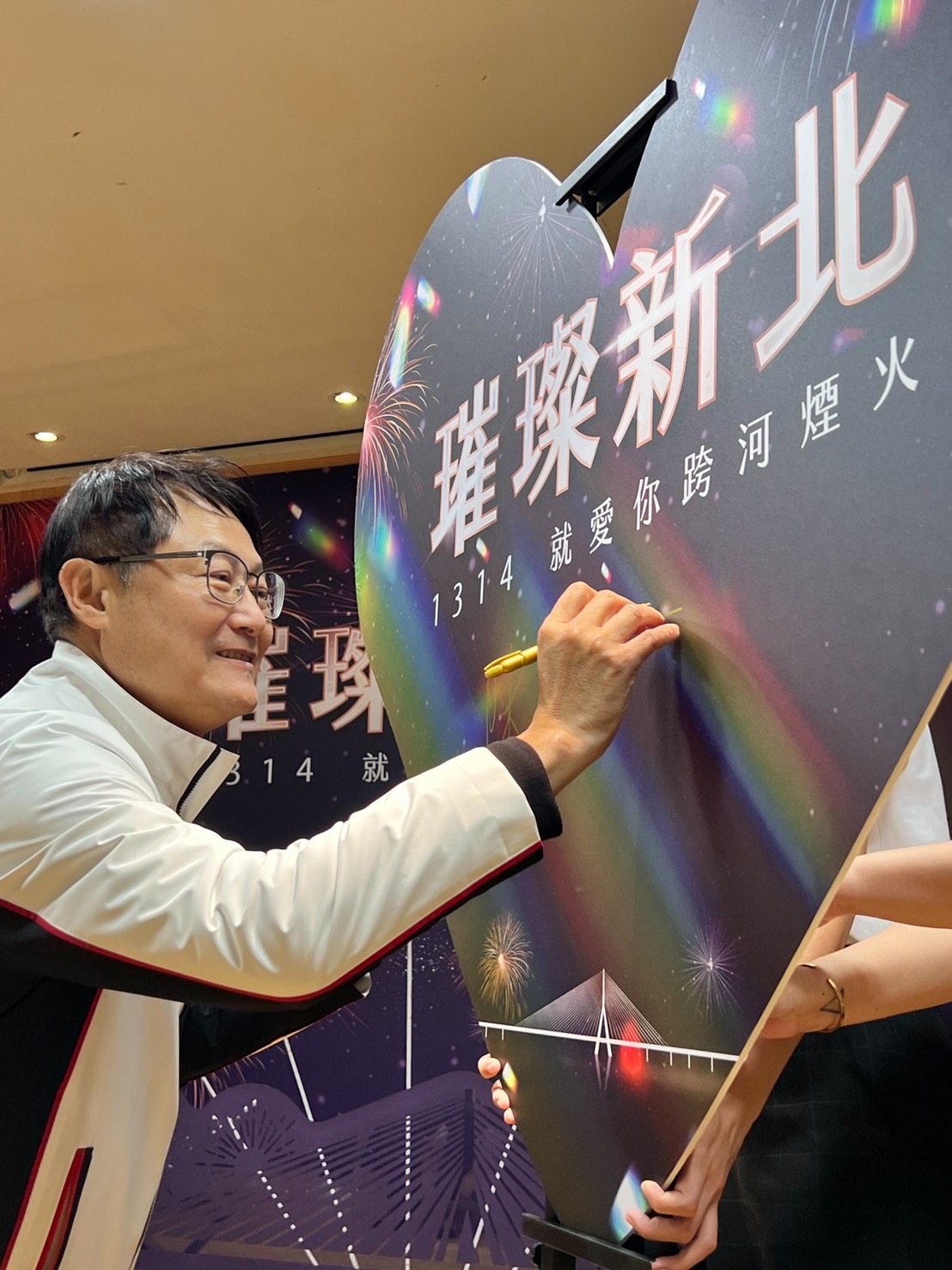 新北市副市長陳純敬在愛心造型板簽名，為今年跨河煙火揭幕